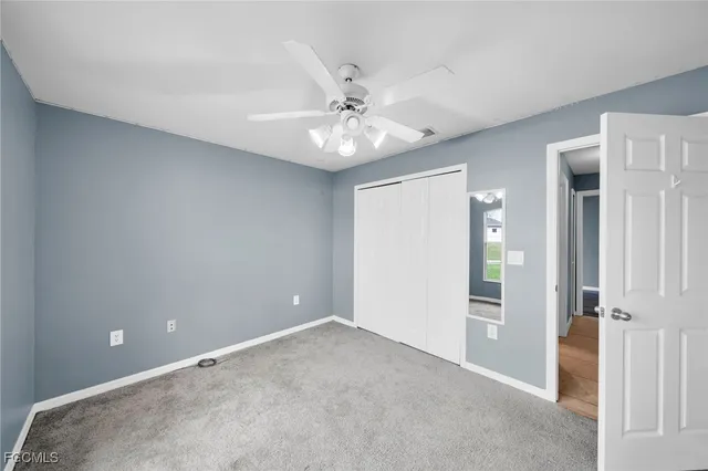 an empty room with closet and a chandelier fan