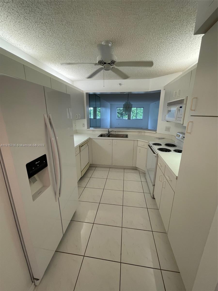 9599 Weldon Circle, Unit A304 Tamarac, FL 33321 - Photo 12 of 12 a kitchen with granite countertop a refrigerator and a stove top oven