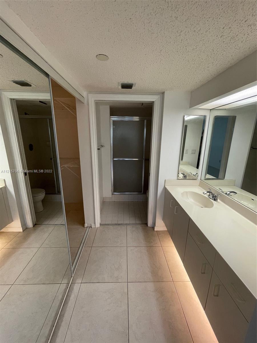 9599 Weldon Circle, Unit A304 Tamarac, FL 33321 - Photo 3 of 12 a bathroom with a double vanity sink and mirror