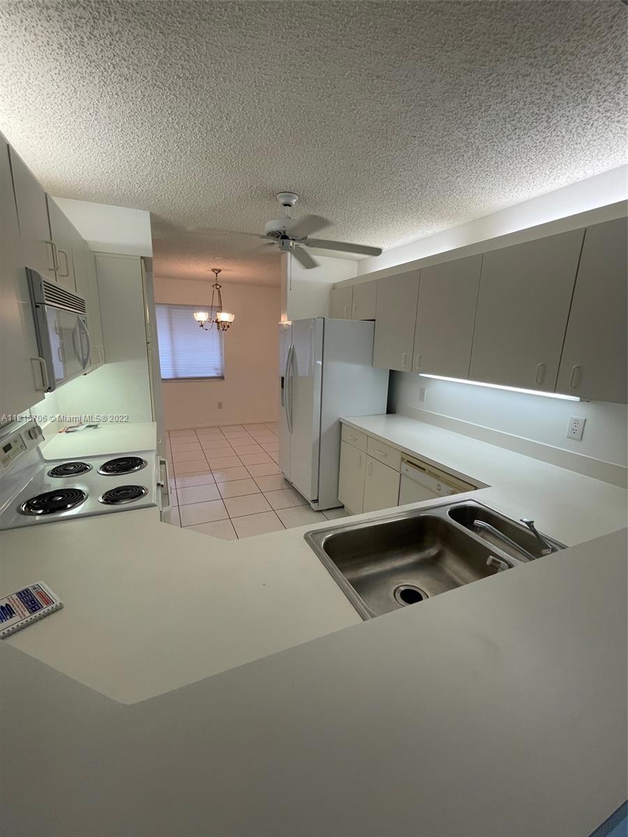 9599 Weldon Circle, Unit A304 Tamarac, FL 33321 - Photo 8 of 12 a kitchen with a sink appliances and cabinets