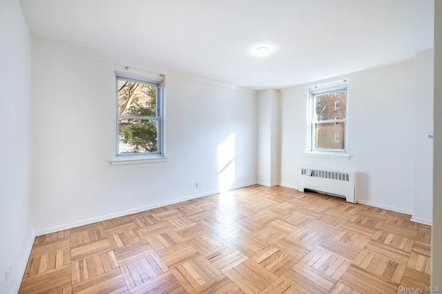 a view of an empty room with window and wooden floor