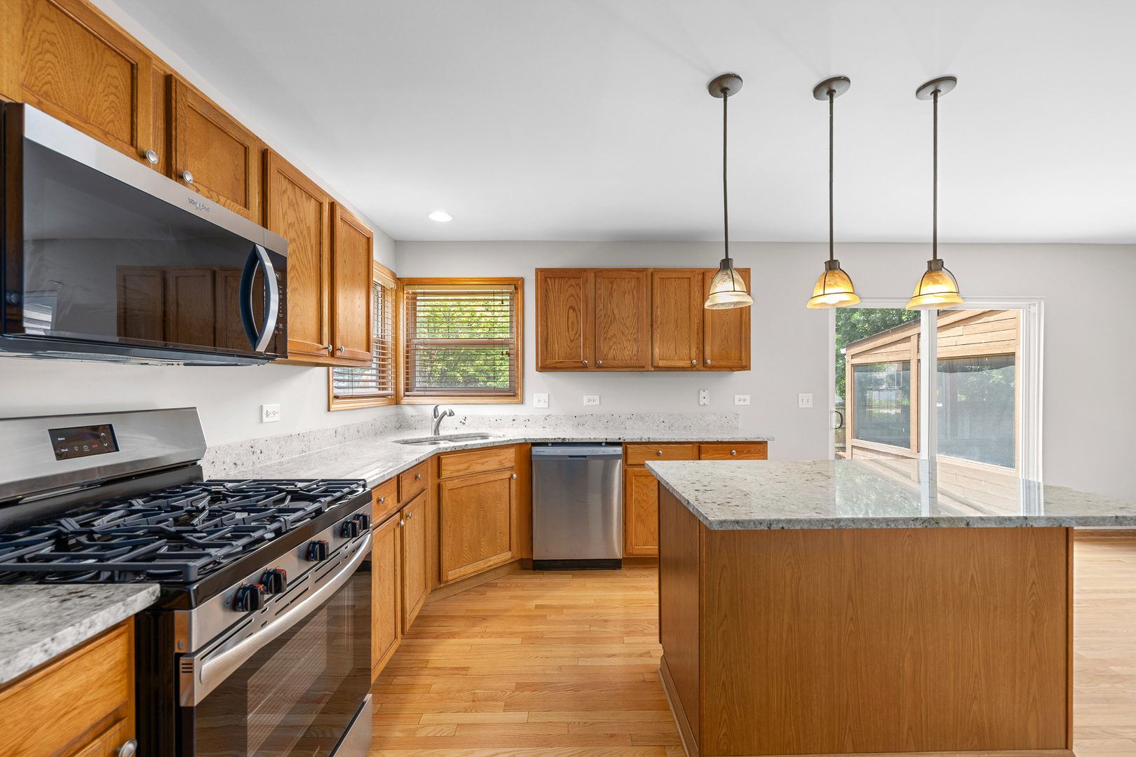 1301 Bridgehampton Drive Plainfield, IL 60586 - Photo 12 of 34 a kitchen with stainless steel appliances granite countertop a stove a sink and a microwave