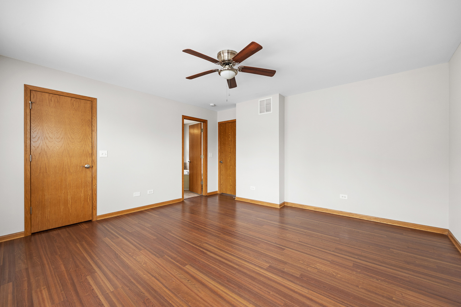 1301 Bridgehampton Drive Plainfield, IL 60586 - Photo 19 of 34 a view of an empty room with wooden floor and a ceiling fan
