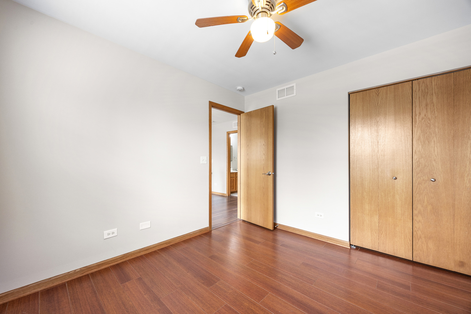 1301 Bridgehampton Drive Plainfield, IL 60586 - Photo 23 of 34 a view of an empty room with wooden floor and a ceiling fan