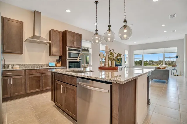 a kitchen with stainless steel appliances granite countertop a sink a stove and a wooden floors