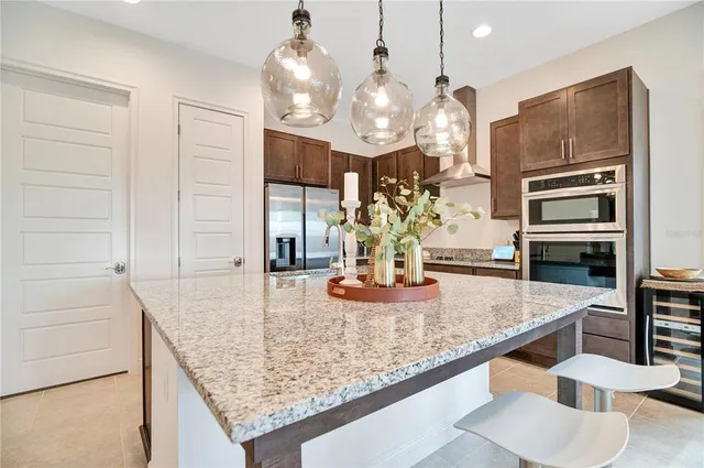 a kitchen with stainless steel appliances kitchen island granite countertop a table and chairs in it