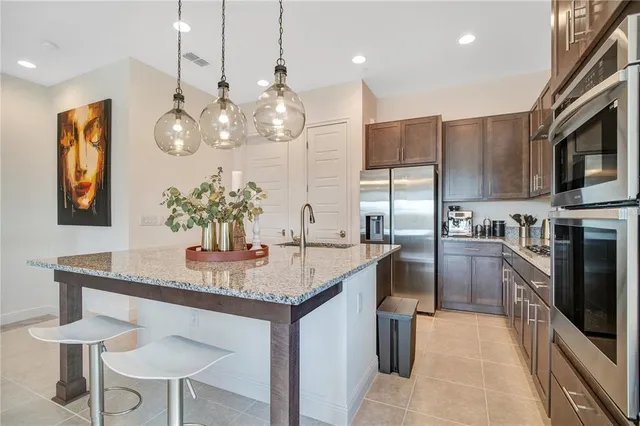 a kitchen with stainless steel appliances kitchen island granite countertop a table chairs and a refrigerator