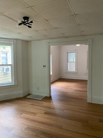 an empty room with wooden floor and windows