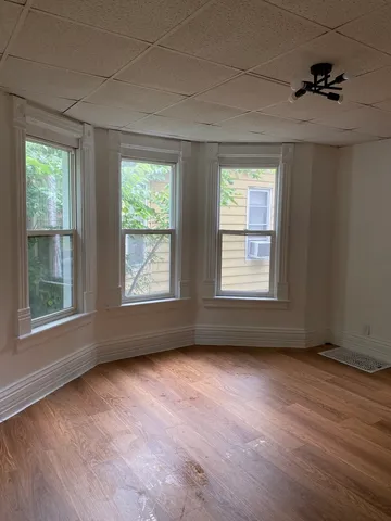 a view of room with hardwood flooring and windows
