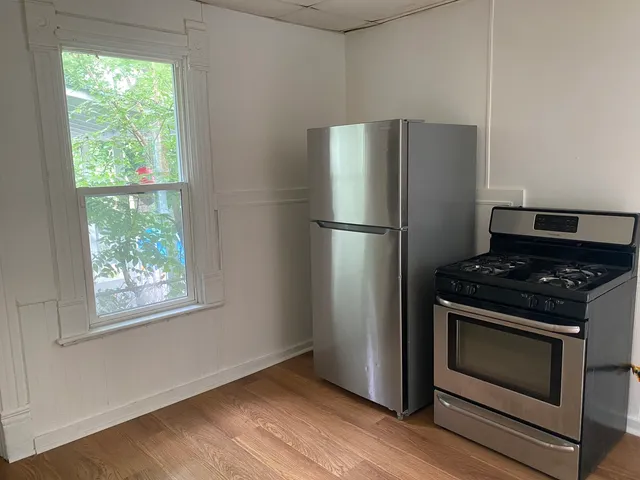 a kitchen with a stove a refrigerator and a wooden floor