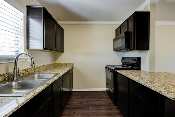 a kitchen with granite countertop a sink and a stove top oven with wooden floor