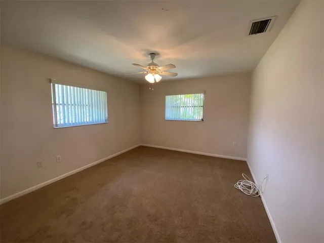 an empty room with windows and ceiling fan