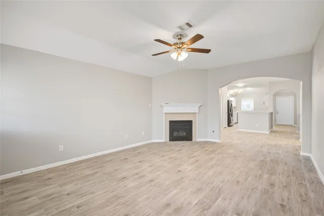 a view of empty room with wooden floor and ceiling fan