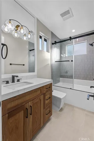a bathroom with a granite countertop sink a toilet a mirror and shower