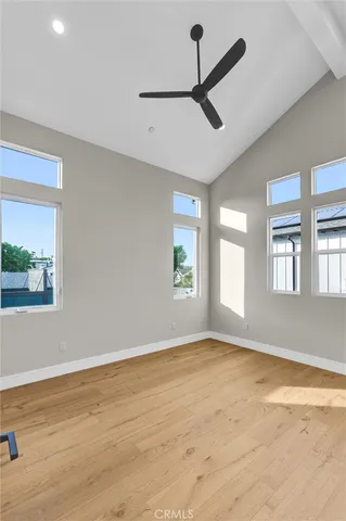 a view of empty room with wooden floor and fan