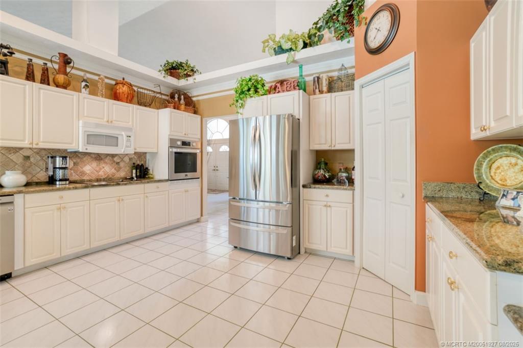 1171 Southeast Buttonwood Circle Stuart, FL 34997 - Photo 13 of 36 a kitchen with stainless steel appliances granite countertop a refrigerator a stove and a sink