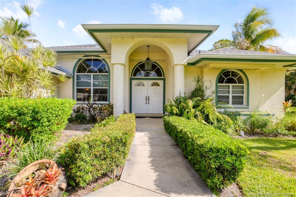 1171 Southeast Buttonwood Circle Stuart, FL 34997 - Photo 2 of 36 a front view of a house with a garden