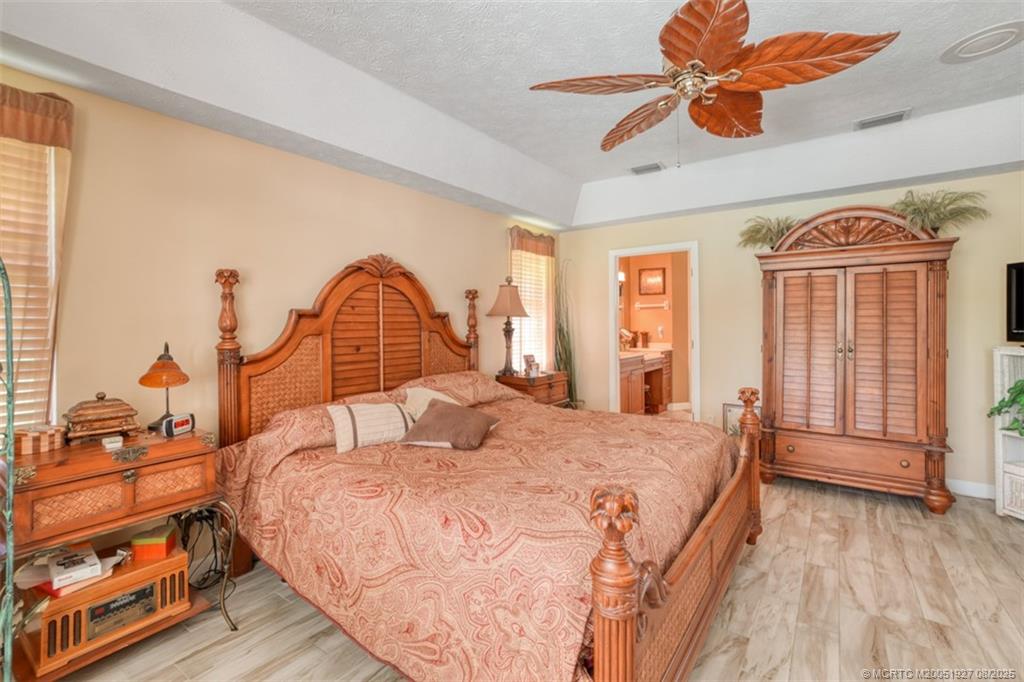 1171 Southeast Buttonwood Circle Stuart, FL 34997 - Photo 25 of 36 a bedroom with a large bed and a chandelier
