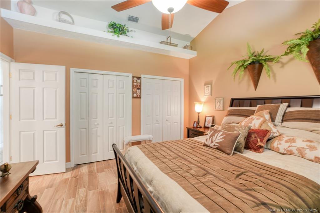 1171 Southeast Buttonwood Circle Stuart, FL 34997 - Photo 29 of 36 a bedroom with a bed and a chandelier