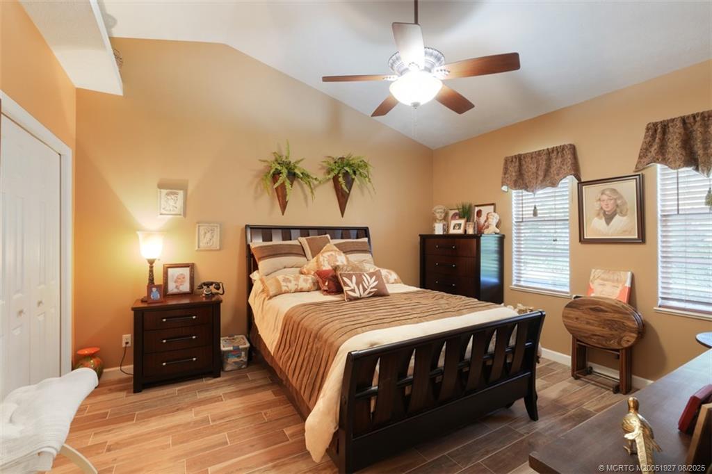 1171 Southeast Buttonwood Circle Stuart, FL 34997 - Photo 30 of 36 a bedroom with a large bed and a chandelier