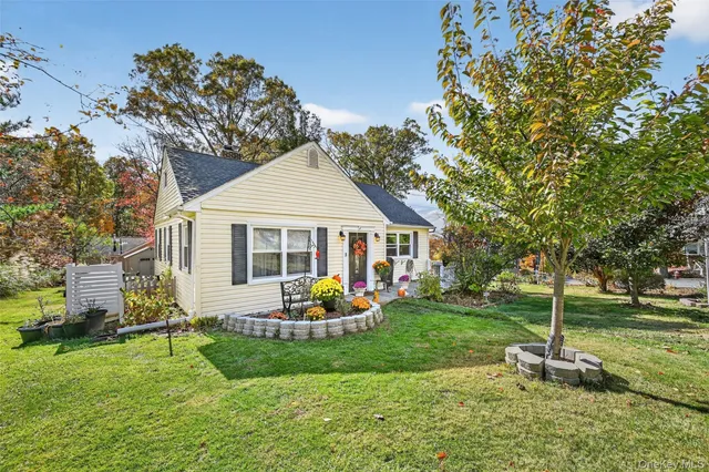 a front view of a house with garden and trees