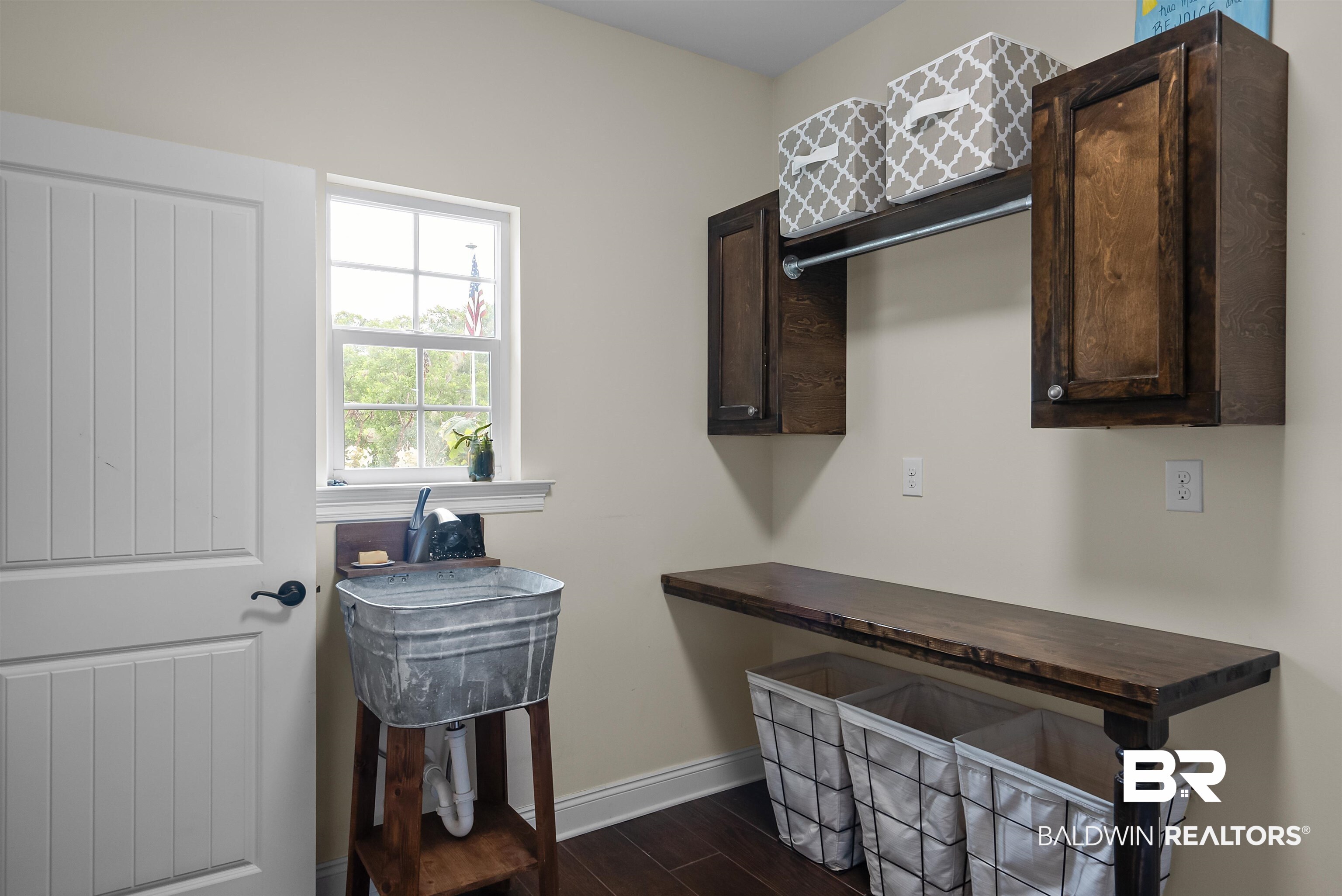 12070 Comalander Road Fairhope, AL 36532 - Photo 36 of 50 Utility space featuring a galvanized wash basin, a white paneled door, dark wood-finish cabinetry, an integrated hanging rod, and a spacious wood-finish counter