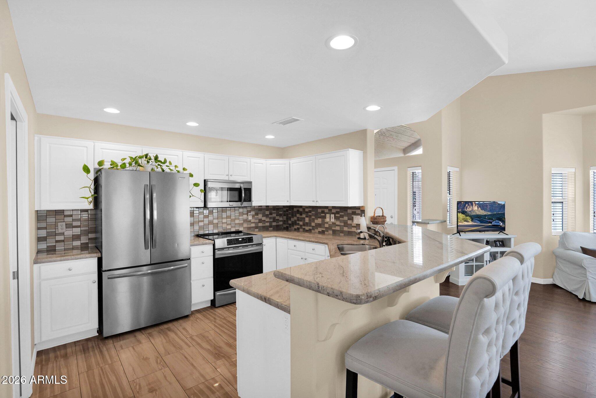 5830 East McKellips Road, Unit 110 Mesa, AZ 85215 - Photo 12 of 45 a kitchen with stainless steel appliances granite countertop a refrigerator a stove a sink a dining table and chairs