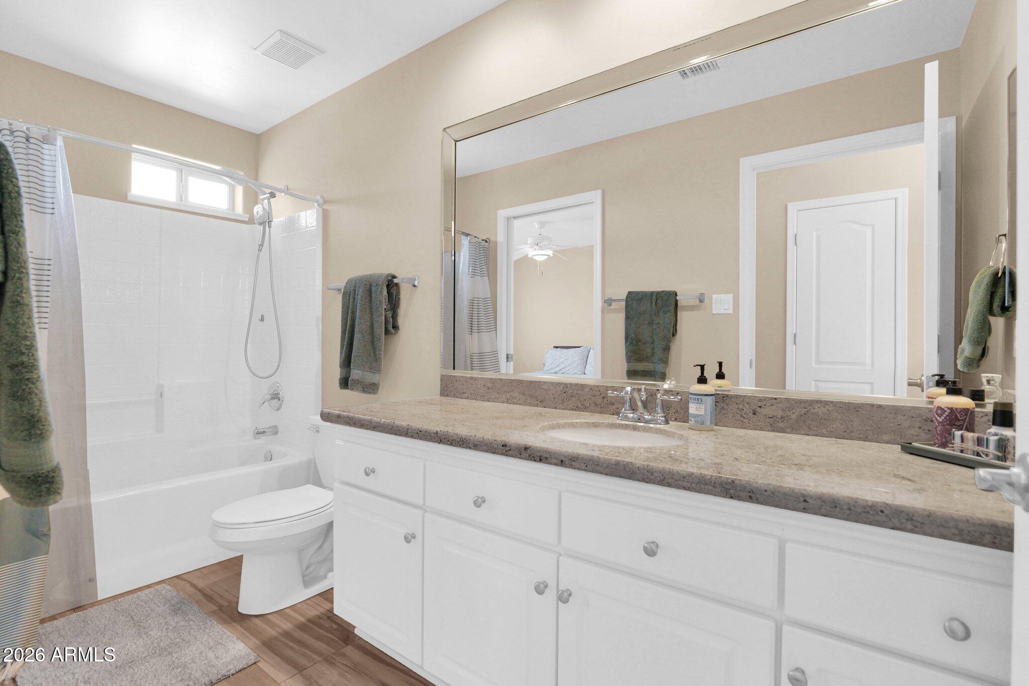 5830 East McKellips Road, Unit 110 Mesa, AZ 85215 - Photo 29 of 45 a bathroom with a granite countertop sink a toilet a mirror and shower