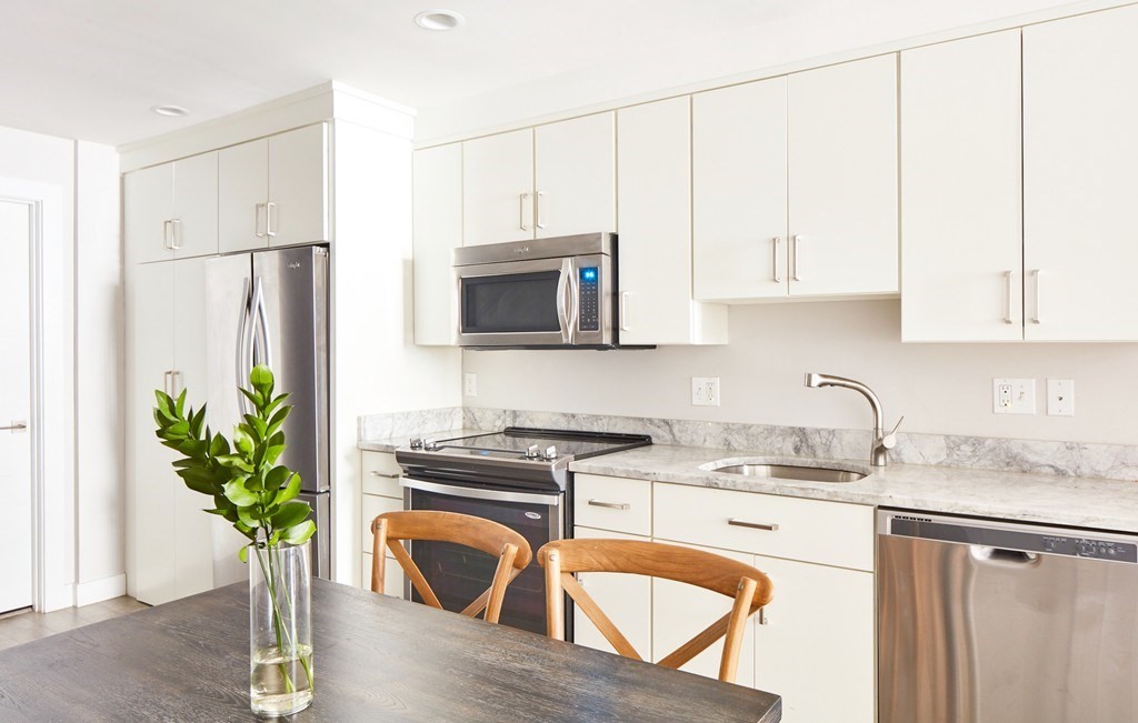 630 Washington Street, Unit 407 Boston, MA 02111 - Photo 2 of 11 a kitchen with stainless steel appliances granite countertop a refrigerator a stove a sink a microwave and cabinets