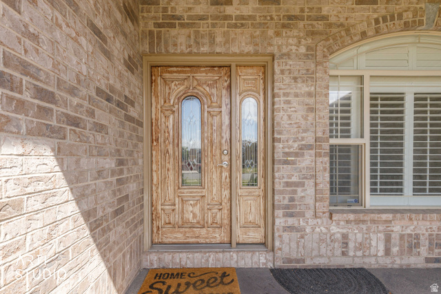 2327 Bluff Ridge Drive Syracuse, UT 84075 - Photo 7 of 66 Brick exterior featuring a paneled wood-finish door with decorative glass inserts and an arched transom window