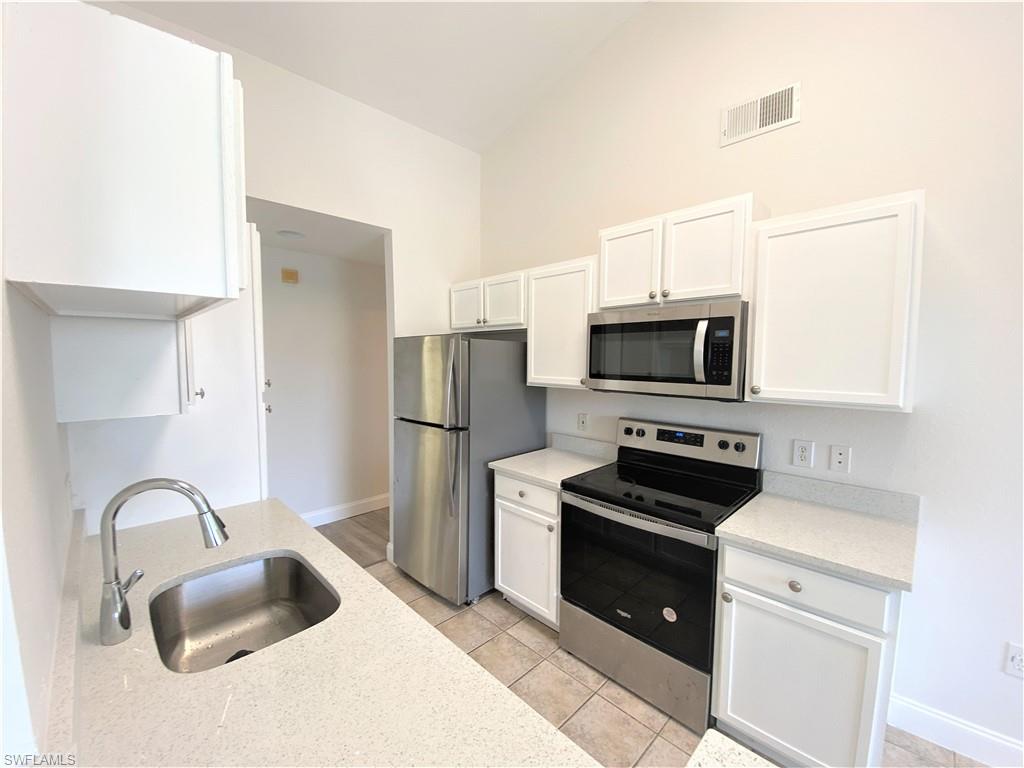 7965 Preserve Circle, Unit 734 Naples, FL 34119 - Photo 8 of 20 a kitchen with sink a microwave a stove and refrigerator
