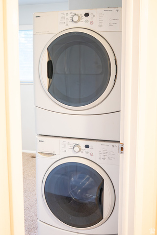 1269 North 400 East, Unit 3 Logan, UT 84341 - Photo 16 of 23 White stacked washer and dryer unit with front-loading doors and visible control panels, set within an interior space featuring light-colored walls and carpeting