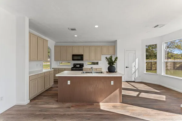 a living room with stainless steel appliances granite countertop a kitchen island a stove a sink dishwasher a microwave oven with cabinets and wooden floor