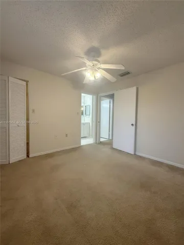 a view of an empty room with a ceiling fan and window