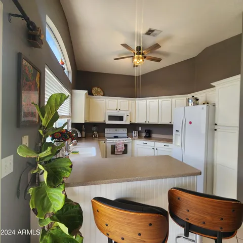 a living room with stainless steel appliances furniture a chandelier and a view of kitchen