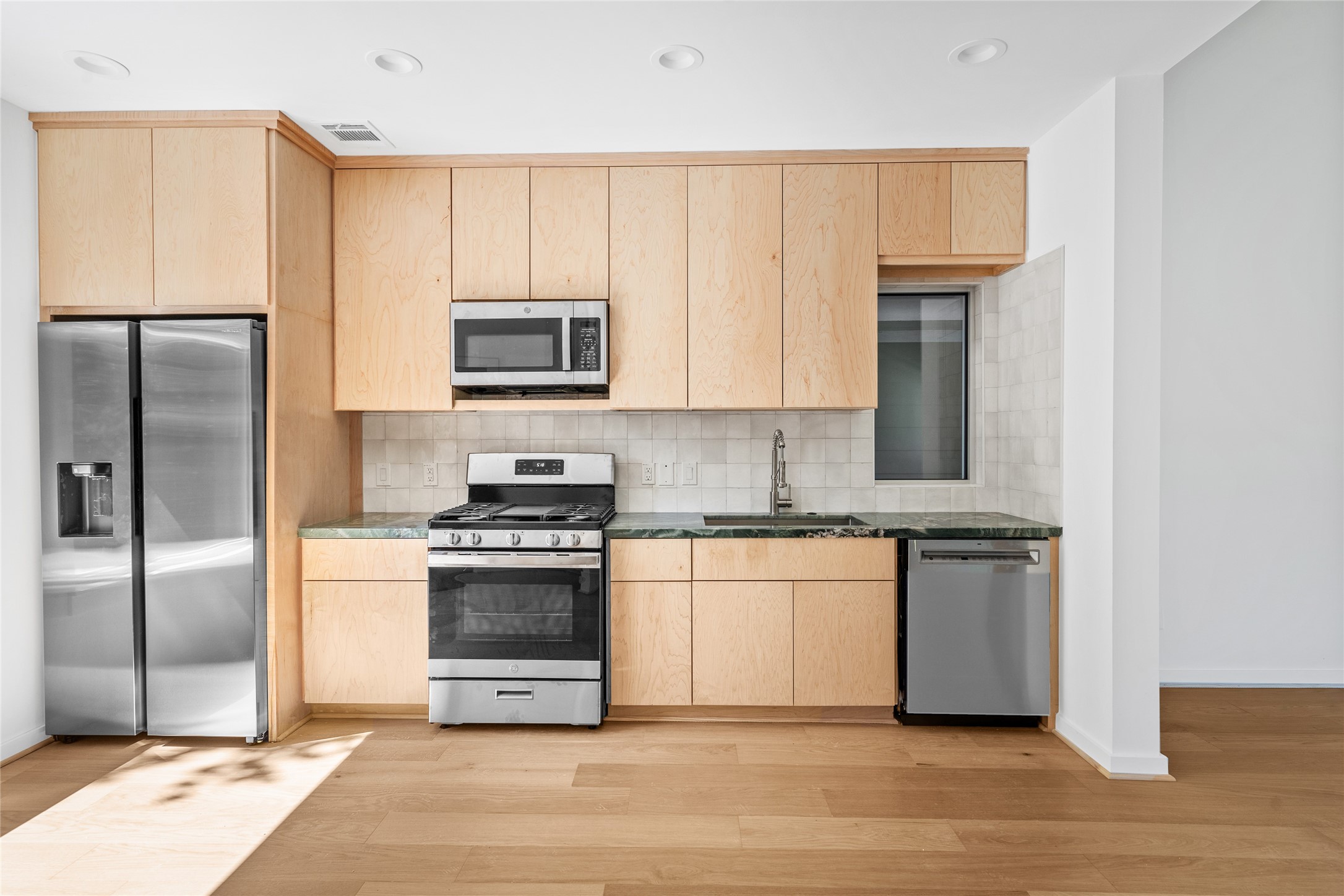 4429 Woodside Street, Unit B Houston, TX 77023 - Photo 10 of 17 a kitchen with stainless steel appliances granite countertop a stove a refrigerator and a microwave