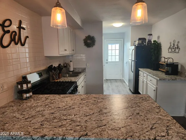 a kitchen with granite countertop a stove a refrigerator and a sink