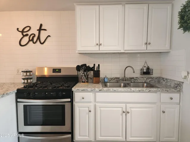 a kitchen with white cabinets and sink