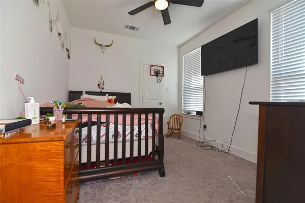a bedroom with furniture a flat screen tv and a ceiling fan