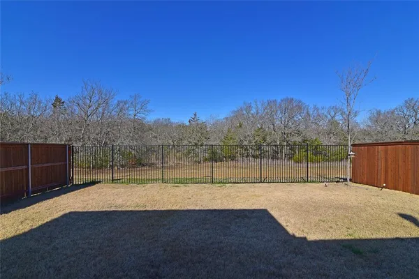 a view of backyard with wooden fence
