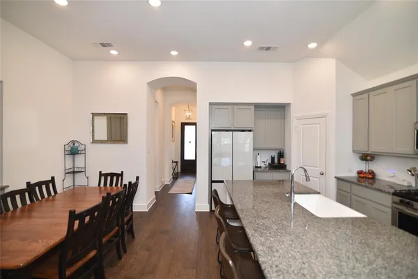 a dining hall with stainless steel appliances granite countertop a stove a sink a dining table and chairs with wooden floor