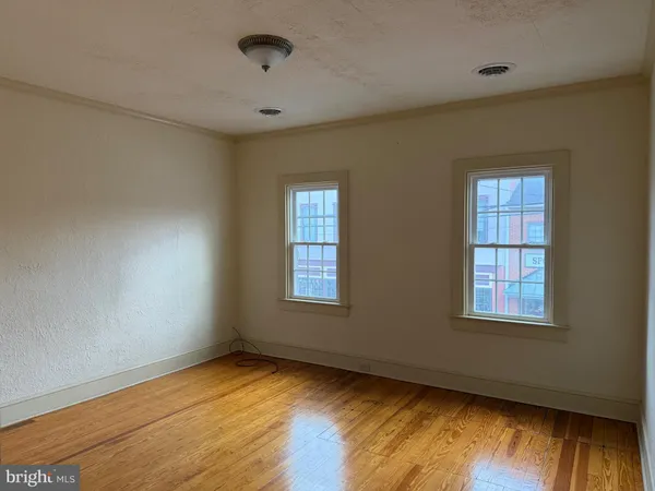 a view of an empty room with wooden floor and window