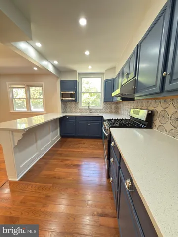 a large kitchen with granite countertop a large counter top space and stainless steel appliances