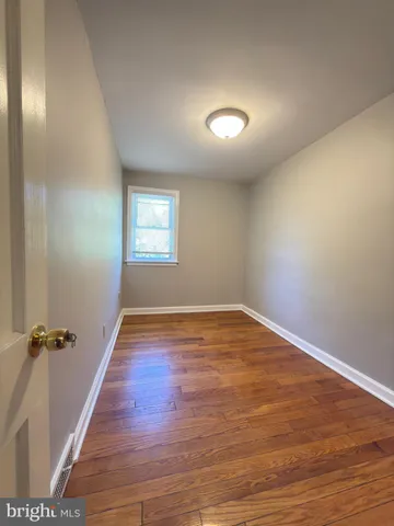 an empty room with wooden floor and window