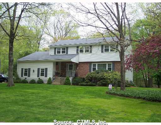 a front view of a house with garden and trees