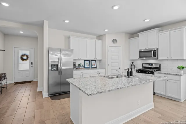 a kitchen with granite countertop a refrigerator a sink a stove a microwave and island