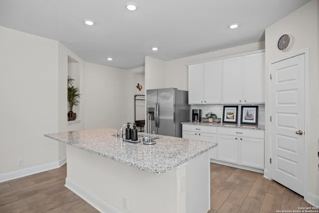 a kitchen with stainless steel appliances granite countertop a sink refrigerator and cabinets