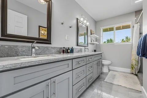 a bathroom with a granite countertop sink mirror and a toilet
