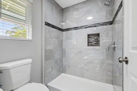 a bathroom with a shower a toilet and a window