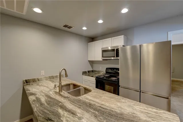 a kitchen with granite countertop a refrigerator and a sink